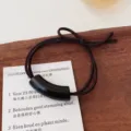 Gedetailleerd opname van een minimalistisch donkerbruin haarelastiekje met zwarte buis. - Cilindrisch / Zwart