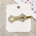 Close-up of a sparkling rhinestone bow hair clip on display card, elegant gold metal hair accessory. - 18# Hair Clip (Overlapped 3D Bowknot)