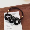 Black resin chain hair tie with brown elastic band and gold metal rings for women daily wear. - Chain / Black