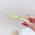 Close-up detail of a gold-toned hairpin featuring white cat's eye stones and pearls. - Round Opal Hair Clip