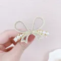 Gedetailleerde opname van een gouden parel strass strik haarspeld met prachtig glinsterende kristallen. - Strik