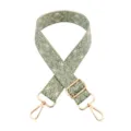 Close-up of woven bag strap detail featuring green leaf pattern and shiny gold metal hardware. - Beige Base Bean Green