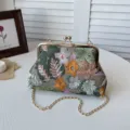 Detailed view of embroidered floral clutch bag with vintage metal frame and stylish chain. - Green