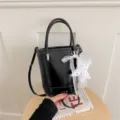 Black leather bucket bag with top handles, crossbody strap and lace star charm detail. - With Pendant / Black