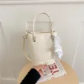 Minimalist white bucket bag detail shot, PU leather, versatile shoulder and handbag style. - With Pendant / White