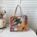 Nahaufnahme einer stylischen Jutetasche mit bunter Pailletten-Blumenstickerei und Knopf. - Orange