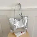 Vue détaillée d'un sac cabas métallisé argenté avec joli pendentif étoile sur table. - Avec Pendentif / Argent