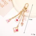 Gold-plated alloy keychain with pink charms featuring heart t-shirt and music note motif - Clothing and Music Note Style