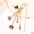 Fashionable gold keychain featuring black and white charms like a hat, bag, and shoe - Fashion Bag and Lipstick Style