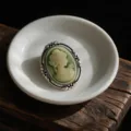 Vintage green cameo brooch featuring an elegant lady profile on a white ceramic dish. - Cameo Portrait Style (Z738)