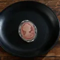 Detailansicht einer Vintage-Cameo-Brosche mit Damenprofil auf einem schwarzen Teller. - Cameo-Porträt-Stil (Z741) / Silber Rot