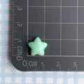 Detailed macro shot showing the exact size of a mini light green resin star charm - Green