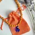Gros plan du pendentif poulpe en verre bleu sur un collier de perles à motif tigre orange. - Collier Pieuvre Bleue Perles Rayées Tigre