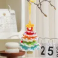 Handgemachter bunter Häkel-Weihnachtsbaumanhänger mit einer kleinen goldener Glocke - Verschneiter Stil M / 1 Stück
