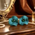 Dettaglio di orecchini a lobo a fiore color petrolio con cristalli verdi taglio smeraldo - Verde