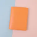 Close-up of bright orange minimalist leather passport cover with visible stitching - Regular Fit / Orange