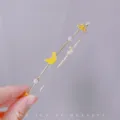 Close-up van een delicate metalen haarband met schattige gele banaan en parelbedels. - Banaan