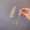 Close-up of the exquisite rhinestone leaf detail on a sleek gold-tone thin hair hoop. - Large Leaf Headband
