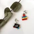 Detailed shot of asymmetric school theme earrings featuring miniature books and blackboard. - Asymmetrical Ear Clips / Colorful