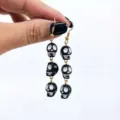 Close-up view of quirky black and white skull dangling earrings, perfect for Halloween party wear. - Black Drop Style