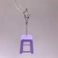 Close-up detail of a creative mini purple stool keychain with a star metal clasp and chain. - Purple