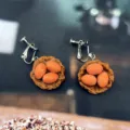 Gros plan de boucles d'oreilles fantaisie artisanales avec nid miniature et œufs en résine. - Boucles d'Oreilles Clips Oeuf au Thé