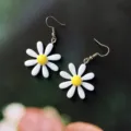 Vue de détail en gros plan des boucles d'oreilles crochets marguerites blanches et jaunes. - Style Crochet / Blanc