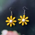 Gros plan détaillé de magnifiques boucles d'oreilles marguerites en acrylique jaune. - Style Crochet / Jaune