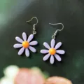 Gros plan détaillé de jolies boucles d'oreilles en acrylique violet avec des cœurs orange. - Style Crochet / Mauve Clair