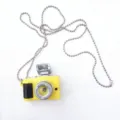 Retro mini camera pendant necklace detail, featuring yellow body and silver chain. - Yellow Camera