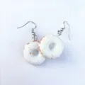 Nahaufnahme der handgemachten Donut-Ohrringe mit süßem weißem Zuckerguss und bunten Streuseln. - Stil D (Ohrhaken) / Weiß