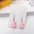 Detaillierte Nahaufnahme von süßen rosa Harz Bär Ohrringen mit Silberhaken auf weißer Karte. - Haken-Stil / Rosa