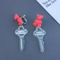 Cute resin bear and glitter key pendant clip-on earrings detail shot for women. - Clip-On Earrings / Burgundy