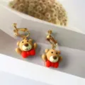 Süße Cartoon Bär Ohrclips mit roter Schleife, goldene Harz Ohrringe für süßen Damen Schmuck. - Ohrclips / Fliege Braunbär