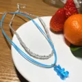 Detailansicht der doppelten Halskette mit weißen Perlen und süßem blauen Bären-Anhänger. - Blau