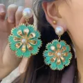 Detailansicht von böhmischen Raffia-Blumenohrringen mit goldenen Blütenblättern. - Cyan