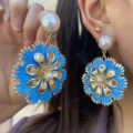 Nahaufnahme von böhmischen blauen Raffia-Blumenohrringen mit goldenen Blütenblättern. - Blau