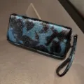 Vista detallada de cartera larga para mujer brillante en azul y negro con correa. - Verde azulado