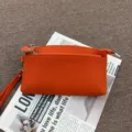 Λεπτομέρεια τσάντας clutch από γνήσιο δέρμα σε πορτοκαλί χρώμα με μαλακή υφή και τσέπες. - Πορτοκαλί