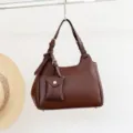 Vista detallada del bolso de hombro de cuero marrón con correa ajustable y mini monedero. - Chocolate