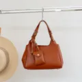 Brown genuine leather women shoulder bag with cute small pouch pendant and metal buckle details. - Caramel color