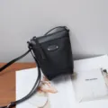 Black genuine leather crossbody bag, compact design with slim strap and metal hardware detail. - Black