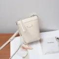 Vista detallada del elegante bolso cruzado de cuero blanco roto, mostrando textura y herrajes finos. - Blanco Roto
