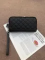 Black quilted leather wallet detail, featuring durable zip closure and convenient wrist strap. - Black