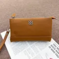Genuine leather coin purse detail shot, brown clutch phone bag with metal clover decoration. - Caramel color
