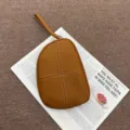 Vista de detalle de un bolso de pulsera de cuero genuino Togo marrón caramelo con costuras. - 20*3*15 cm / Caramelo