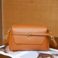 Primer plano del bolso de hombro de cuero marrón vintage, con textura y hebilla. - Nogal