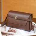 Primer plano detalle de bolso bandolera vintage de cuero marrón con hebilla de metal. - Marrón