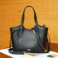 Vista detallada del bolso tote de cuero negro con textura suave y herrajes metálicos. - Negro