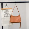 Detail view of the brown leather shoulder bag, premium cowhide, elegant curved design for women. - 25*9*17CM / Caramel color